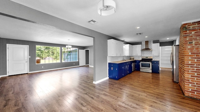 kitchen featuring light wood-type flooring, stainless steel appliances, wall chimney exhaust hood, white cabinets, and blue cabinetry