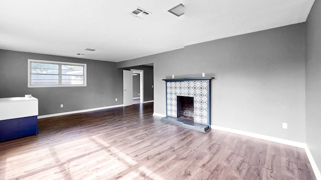 unfurnished living room with hardwood / wood-style floors and a tile fireplace