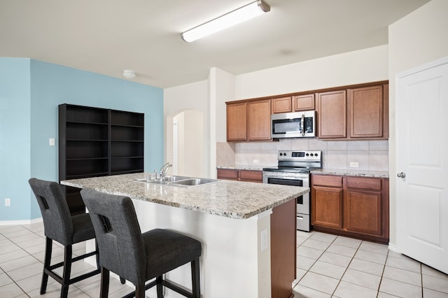 kitchen featuring stainless steel appliances, decorative backsplash, sink, and a center island with sink