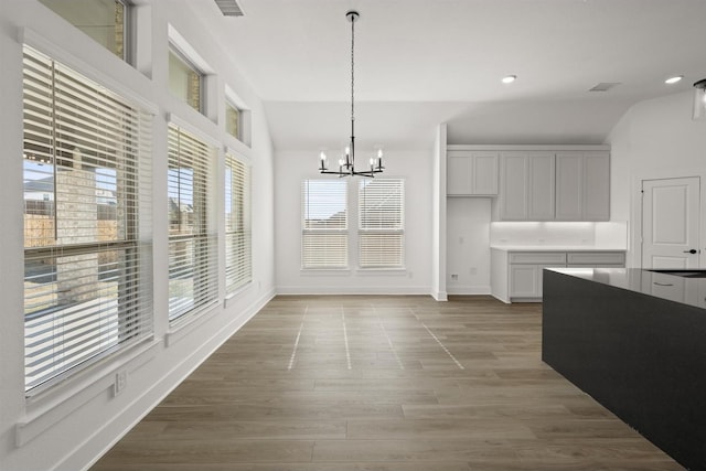 dining area featuring vaulted ceiling, a chandelier, and light hardwood / wood-style flooring