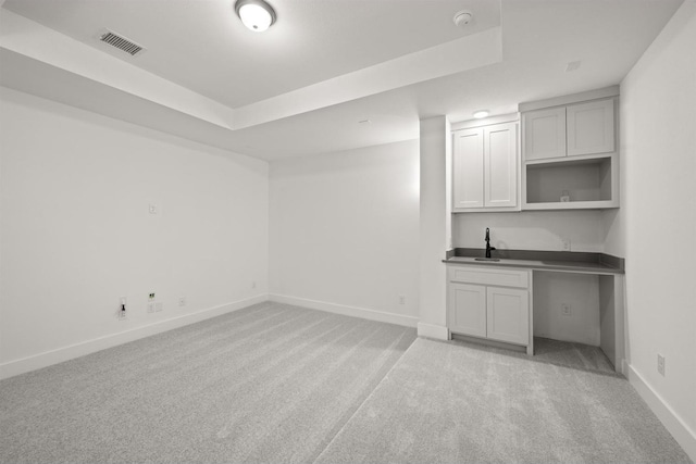 carpeted empty room featuring a tray ceiling