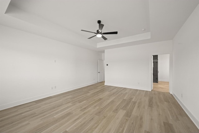 spare room featuring ceiling fan, a tray ceiling, and light wood-type flooring