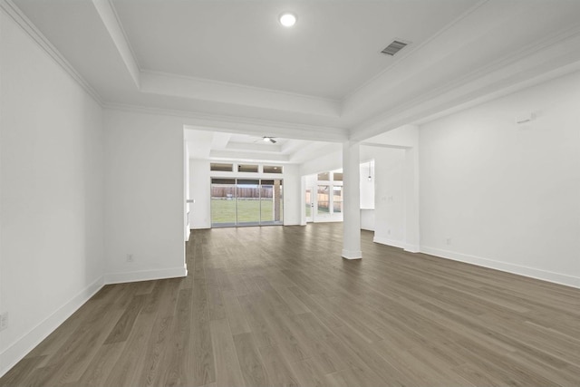 unfurnished living room with dark wood-type flooring, a tray ceiling, and ornamental molding