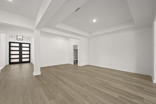 unfurnished living room with wood-type flooring, a raised ceiling, and french doors