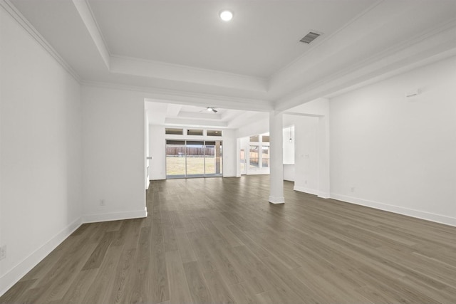 unfurnished living room featuring a raised ceiling, dark wood-type flooring, and crown molding