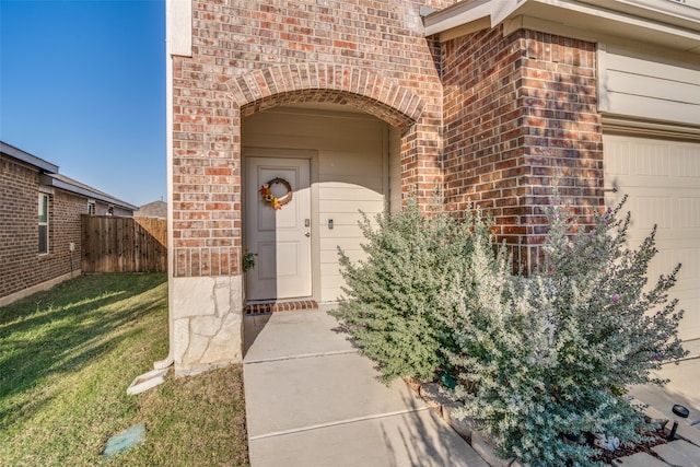 view of exterior entry with a garage and a yard