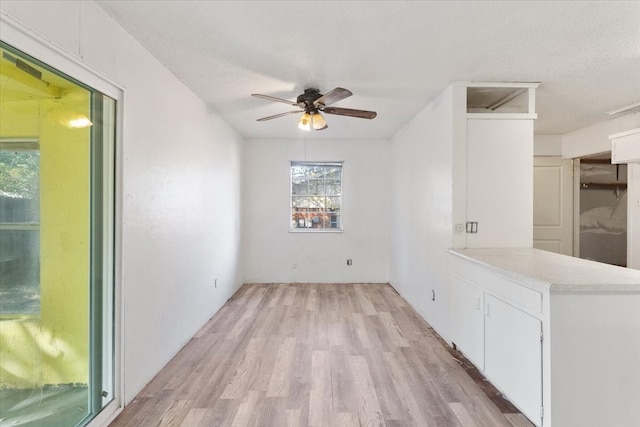 unfurnished dining area featuring light hardwood / wood-style flooring, a textured ceiling, and ceiling fan