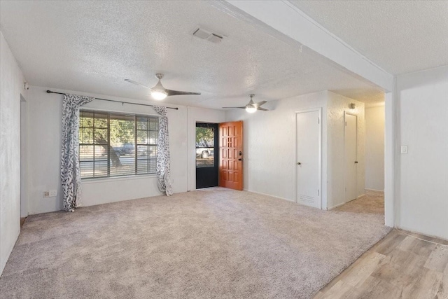 unfurnished living room featuring visible vents, a ceiling fan, and a textured ceiling