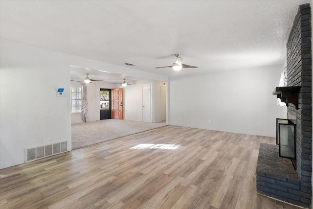 unfurnished living room with a ceiling fan, visible vents, and wood finished floors