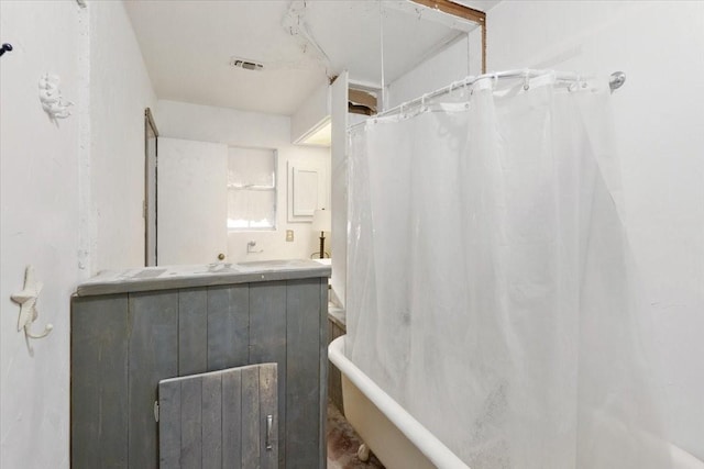 bathroom featuring a washtub, a shower with curtain, visible vents, and vanity