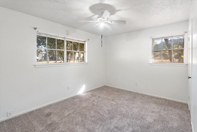 carpeted spare room with a wealth of natural light, a textured ceiling, and ceiling fan