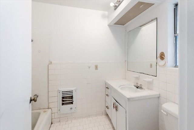 bathroom featuring tile walls, toilet, heating unit, and vanity