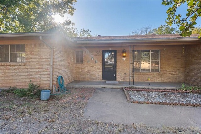 property entrance featuring a porch and brick siding