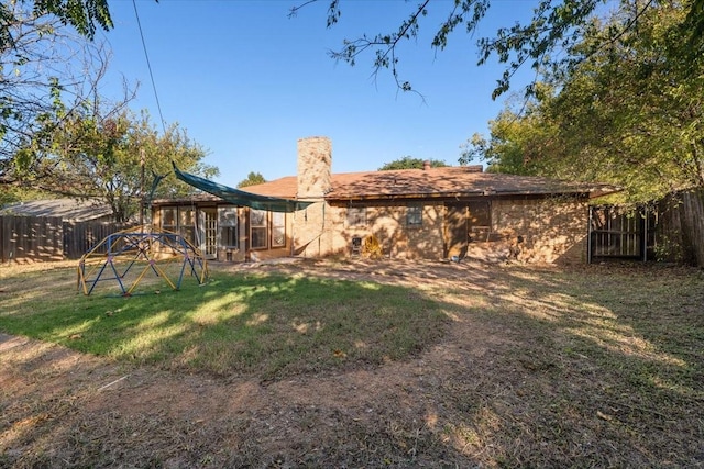 rear view of property featuring a lawn, a chimney, and a fenced backyard