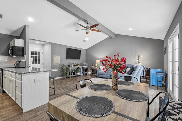 dining space featuring vaulted ceiling with beams, hardwood / wood-style flooring, and ceiling fan