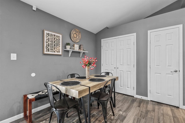 dining space with dark wood-type flooring and vaulted ceiling