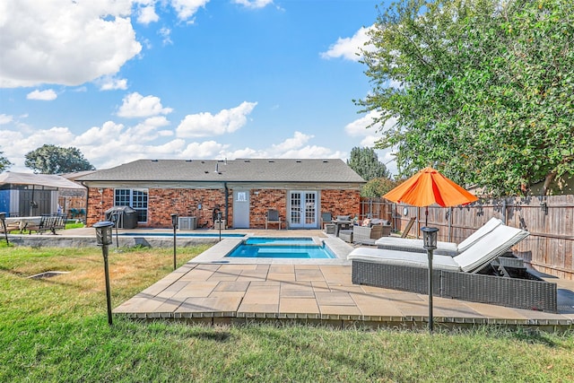 view of pool with french doors, central air condition unit, a patio, and a lawn