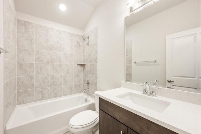 full bathroom with toilet, vanity, lofted ceiling, and tiled shower / bath