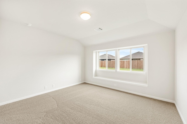 spare room featuring carpet floors and vaulted ceiling