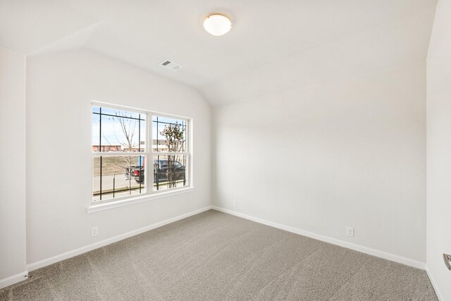 spare room featuring carpet flooring and vaulted ceiling