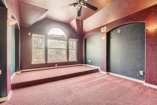 carpeted spare room featuring a textured ceiling, ceiling fan, and vaulted ceiling