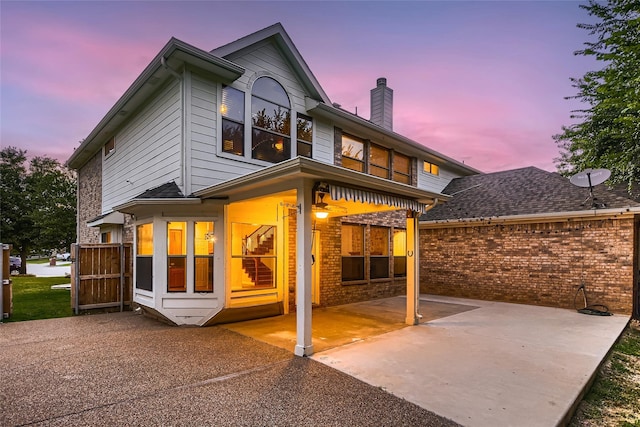 back house at dusk featuring a patio