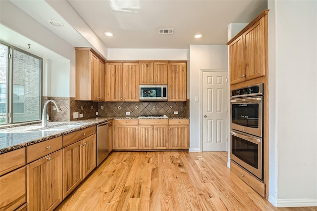 kitchen with sink, plenty of natural light, light hardwood / wood-style floors, stainless steel appliances, and light stone counters