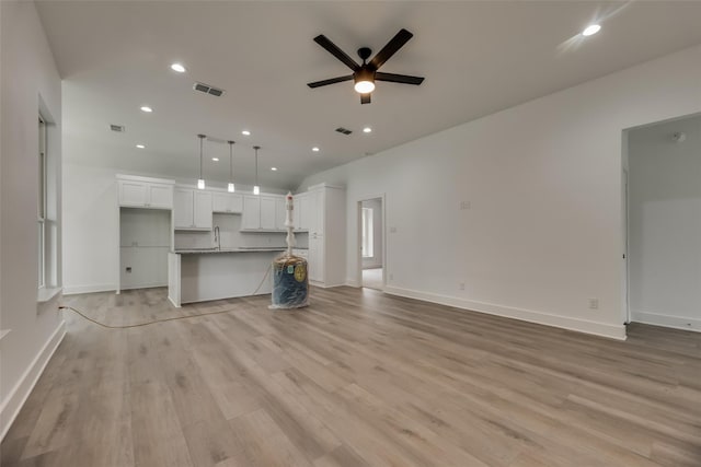 unfurnished living room featuring sink, light wood-type flooring, and ceiling fan