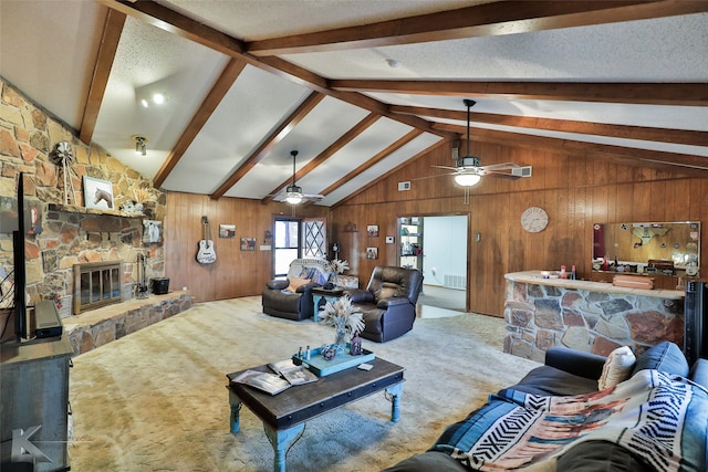 living room with vaulted ceiling with beams, wood walls, a stone fireplace, and carpet floors