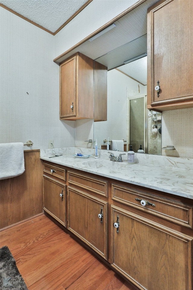 kitchen featuring light stone countertops, ornamental molding, a textured ceiling, dark wood-type flooring, and sink