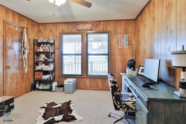 carpeted office with a textured ceiling, ceiling fan, and wood walls