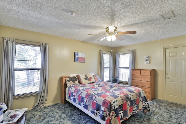 carpeted bedroom with ceiling fan, a textured ceiling, and multiple windows