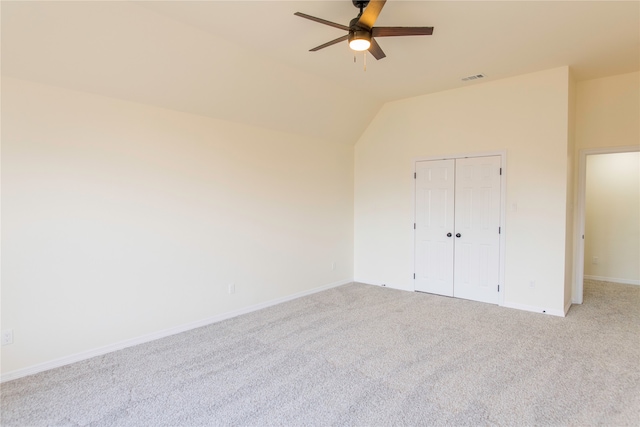 unfurnished bedroom with a closet, ceiling fan, light carpet, and vaulted ceiling