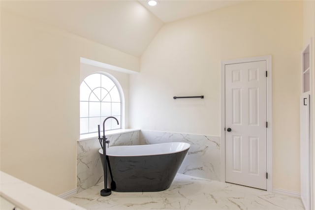 bathroom featuring a tub, tile walls, and lofted ceiling