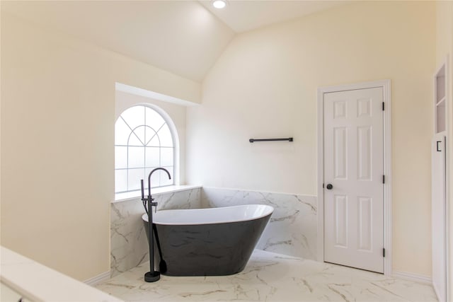 3004 Normandy Dr, Mckinney, TX 75070 - bathroom featuring marble finish floors, a freestanding tub, lofted ceiling, a wainscoted wall, and tile walls