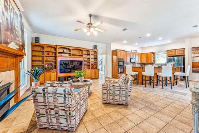 living room featuring crown molding, a fireplace, light tile patterned flooring, and ceiling fan