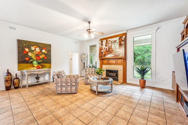 tiled living room with ceiling fan, ornamental molding, and a fireplace