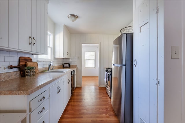 kitchen featuring tasteful backsplash, appliances with stainless steel finishes, sink, dark hardwood / wood-style flooring, and white cabinets