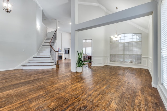 unfurnished living room featuring high vaulted ceiling, dark wood-type flooring, and a chandelier