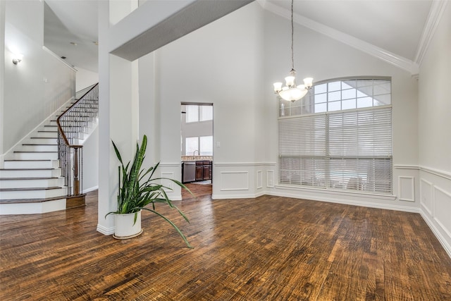 unfurnished dining area with dark wood-type flooring, ornamental molding, high vaulted ceiling, and a notable chandelier