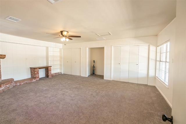 unfurnished bedroom with carpet flooring, ceiling fan, and two closets