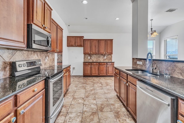 kitchen with lofted ceiling, decorative backsplash, sink, decorative light fixtures, and stainless steel appliances