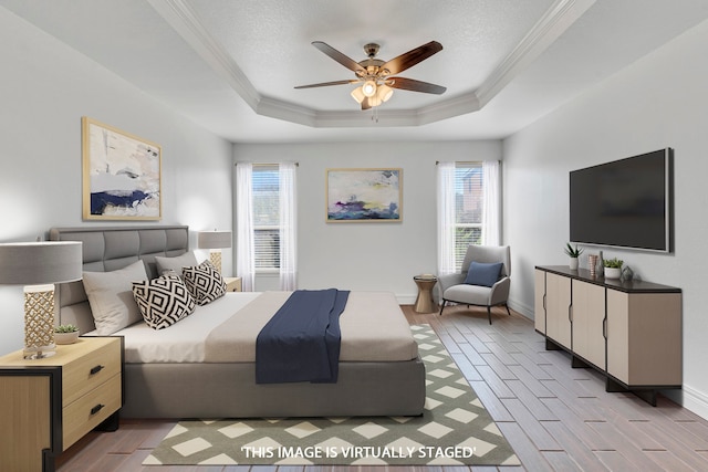 bedroom featuring light wood-type flooring, a textured ceiling, a tray ceiling, ceiling fan, and crown molding