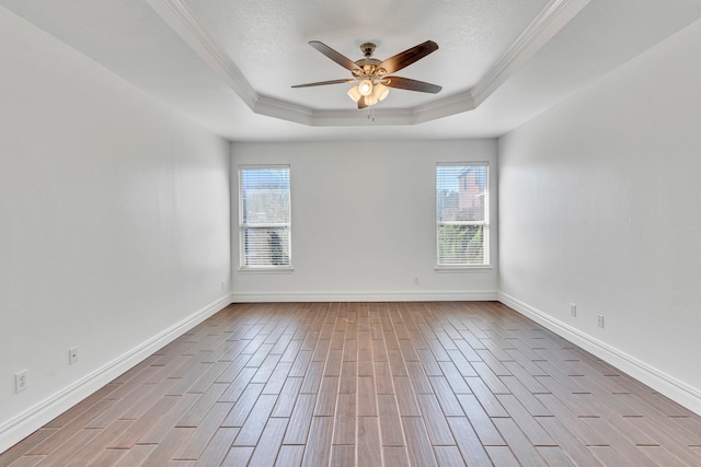 unfurnished room featuring a raised ceiling, ceiling fan, light hardwood / wood-style floors, and plenty of natural light