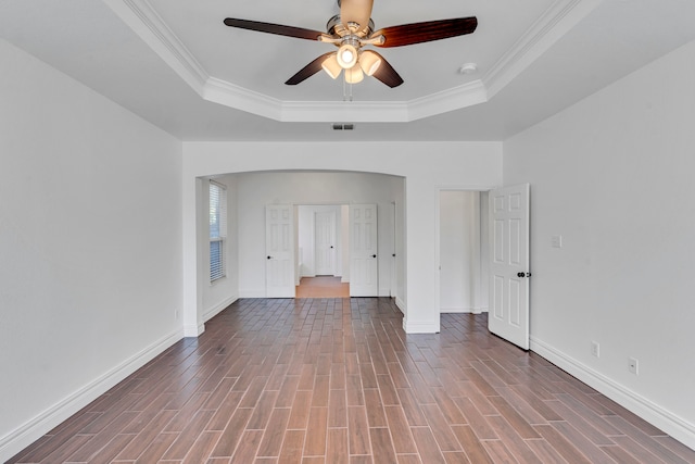 empty room with ceiling fan, a raised ceiling, and wood-type flooring