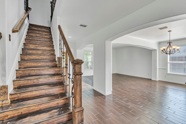 staircase with a chandelier and hardwood / wood-style floors