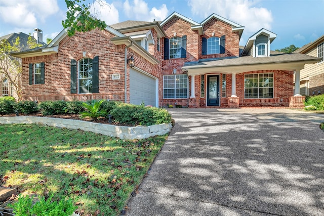 view of front of home with a garage, a front yard, and covered porch