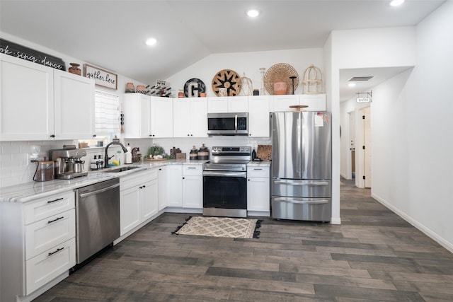 kitchen featuring visible vents, white cabinets, vaulted ceiling, stainless steel appliances, and a sink