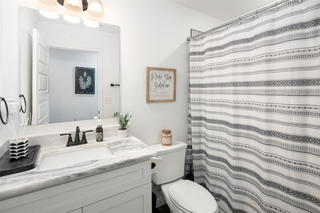 bathroom featuring toilet, a shower with shower curtain, and vanity