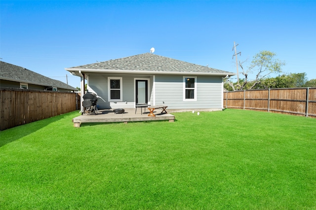 rear view of property featuring roof with shingles, a yard, and a fenced backyard